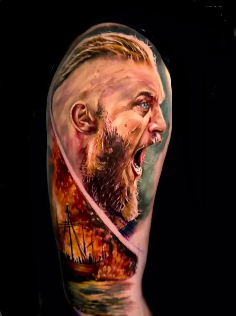 Schreiender Wikinger vor brennendem Drachenschiff, Colour-Realistic-Tattoo auf dem Oberarm – Arbeit von Alex Dummmi, Riverside Ink St. Margrethen