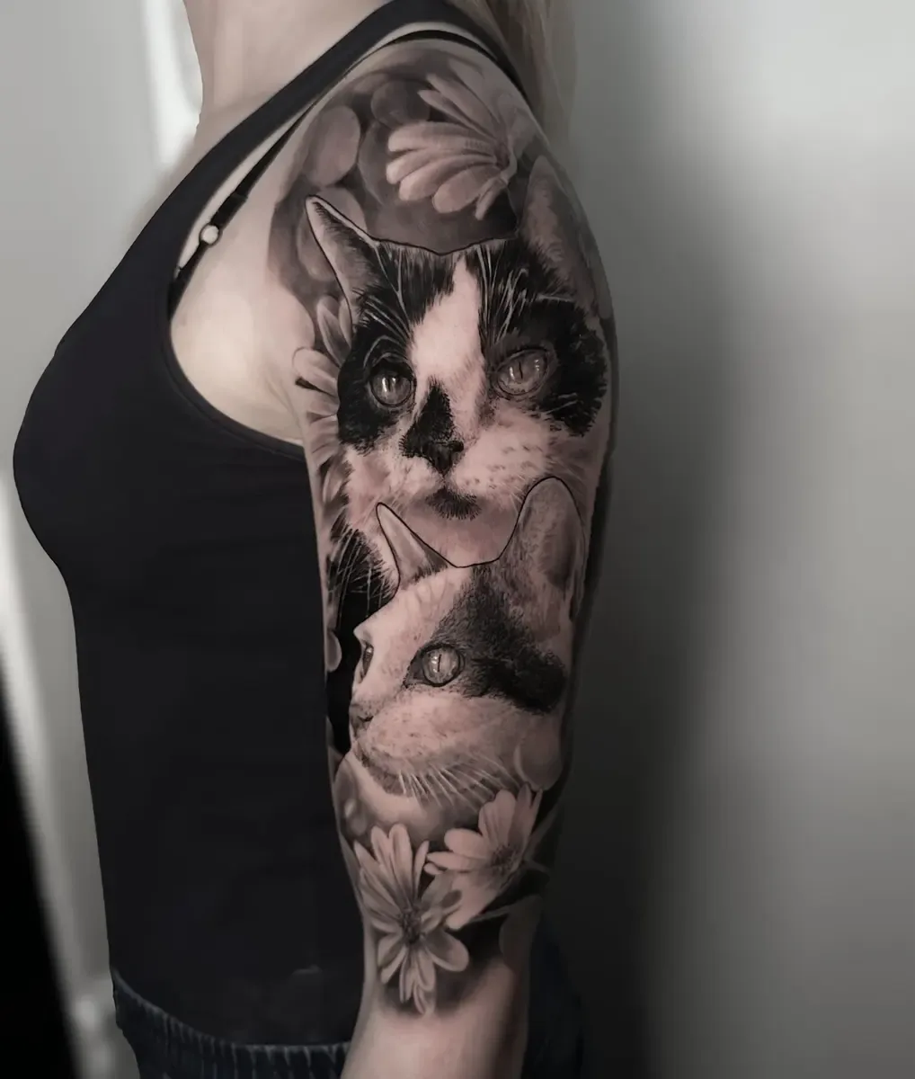 Katzenportrait mit Blumen, Black-and-Grey-Realistic-Tattoo auf dem Oberarm – Arbeit von Bela BL, Riverside Ink St. Margrethen