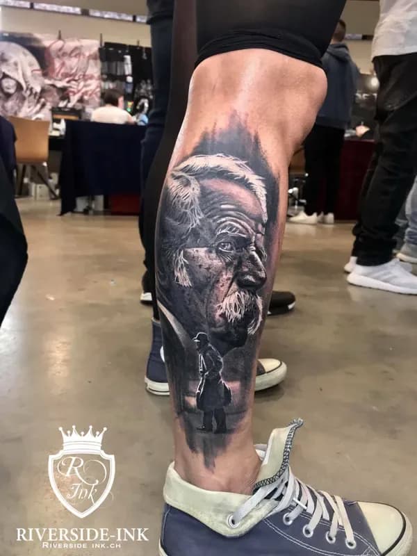 Porträt eines älteren Mannes mit kleiner Figur, Black-and-Grey-Realistic-Tattoo am Unterschenkel – Arbeit von Gusztav, Riverside Ink St. Margrethen