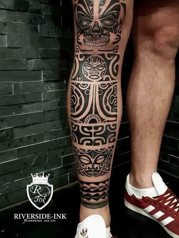 Tribal-Muster mit Gesichtsmasken, Maori-Tattoo am Bein – Arbeit von Marko Clown, Riverside Ink St. Margrethen