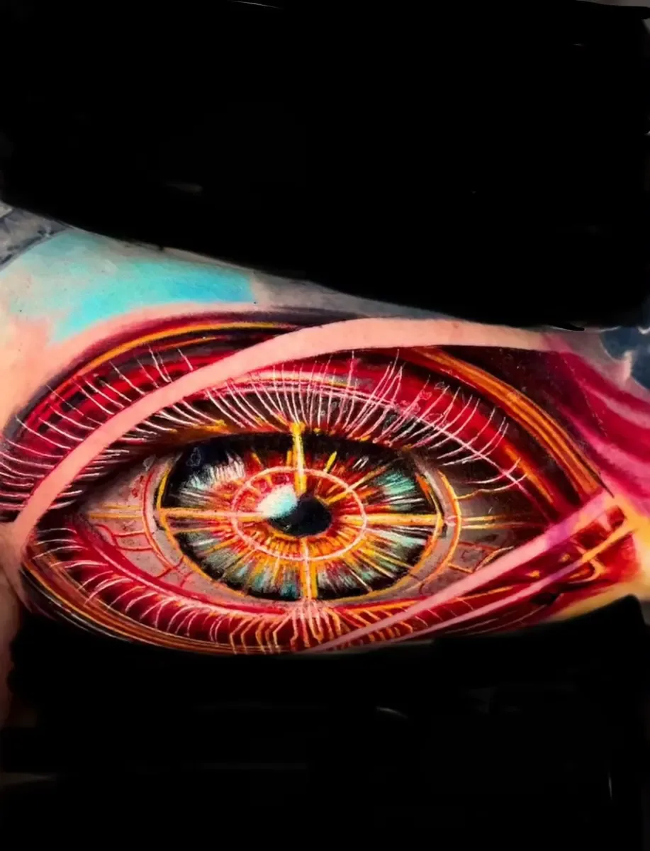 Realistisches Auge in Rot- und Goldtönen, Colour-Realistic-Tattoo am Arm – Arbeit von Alex Dummmi, Riverside Ink St. Margrethen