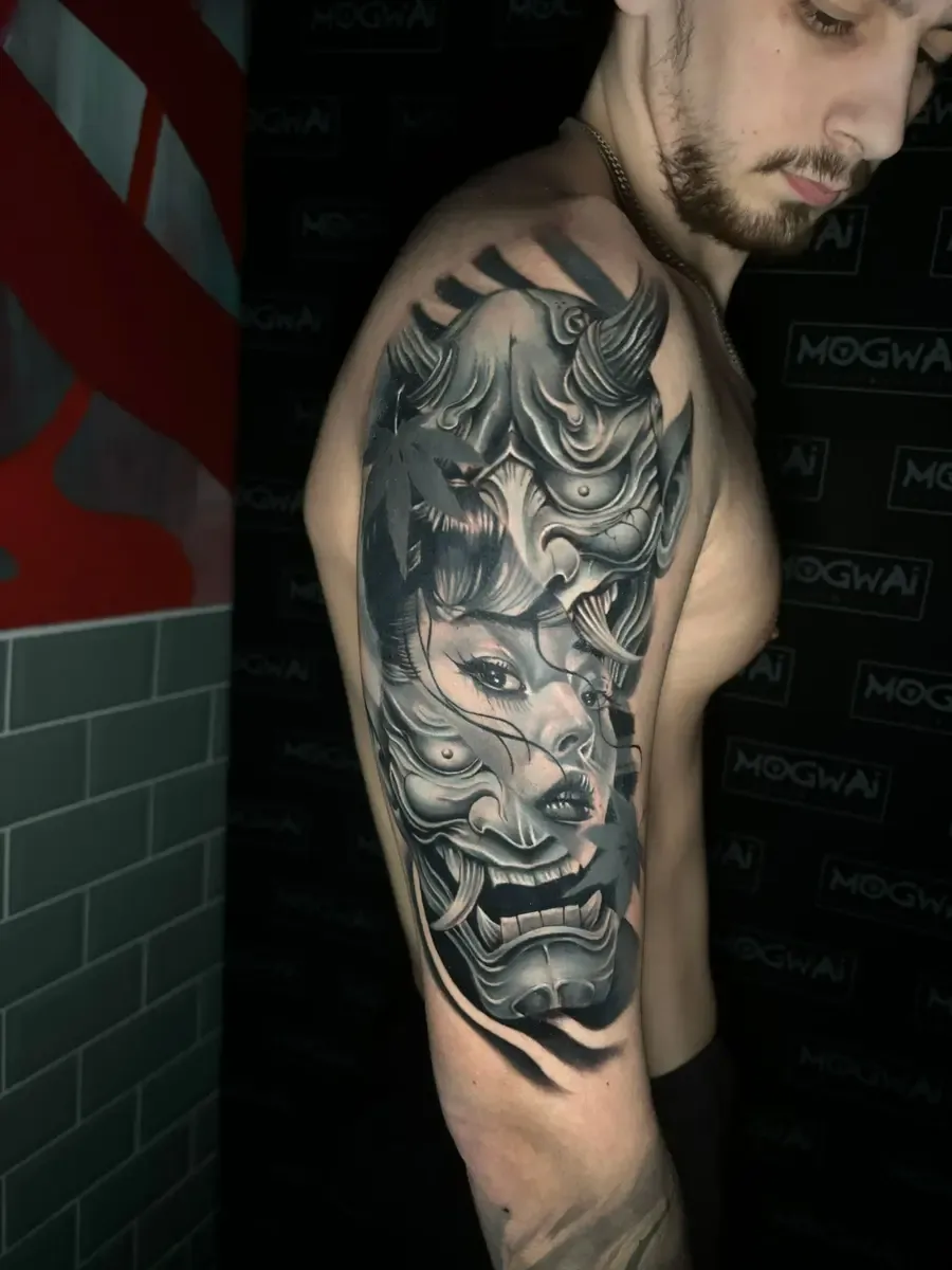 Oni-Maske mit Geishagesicht, Black-and-Grey-Tattoo auf dem Oberarm – Arbeit von Marco Carbonaro, Riverside Ink St. Margrethen