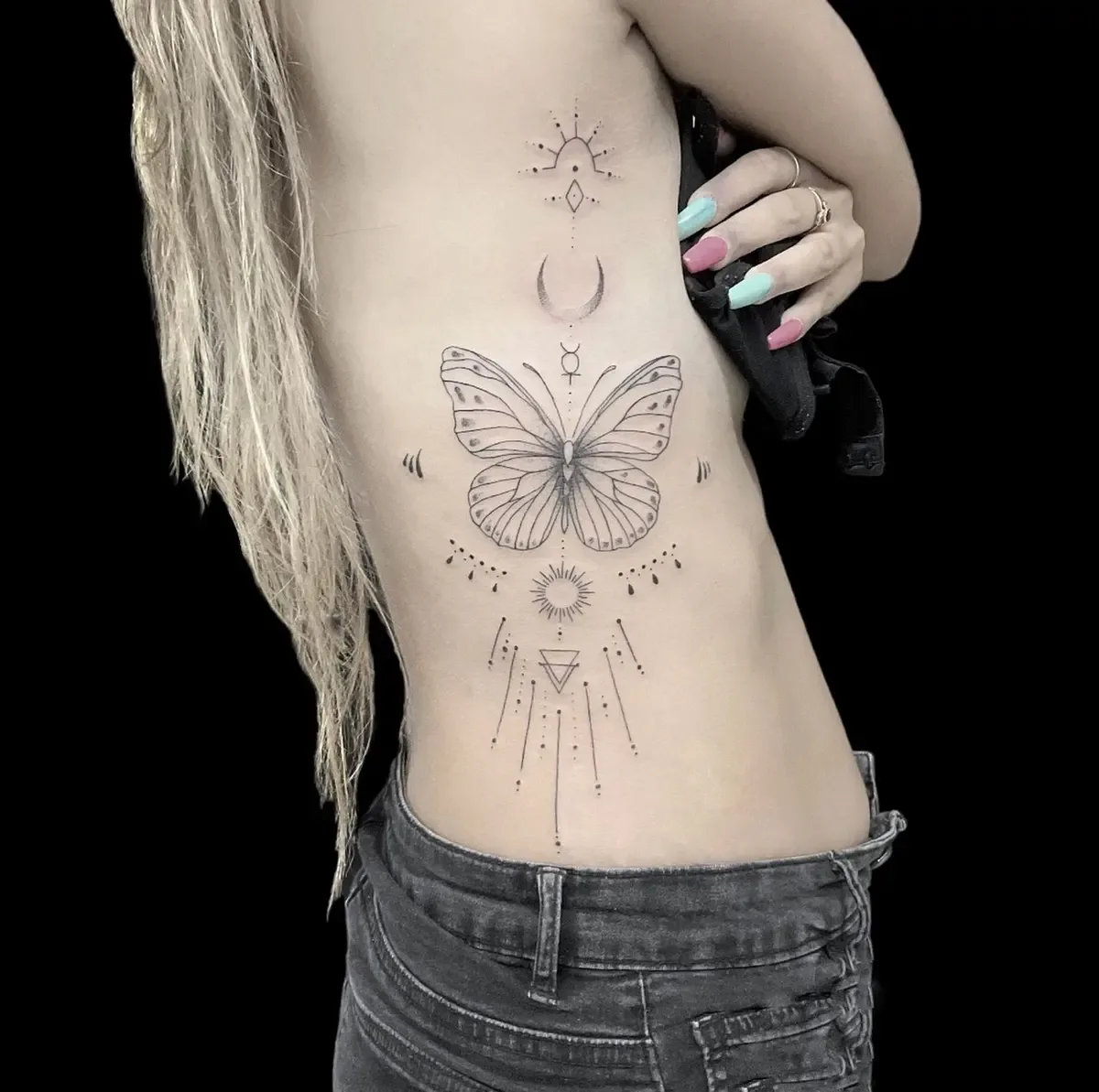 Schmetterling mit Mond und Sonne, Fineline-Tattoo an den Rippen – Arbeit von Mr. George, Riverside Ink St. Margrethen
