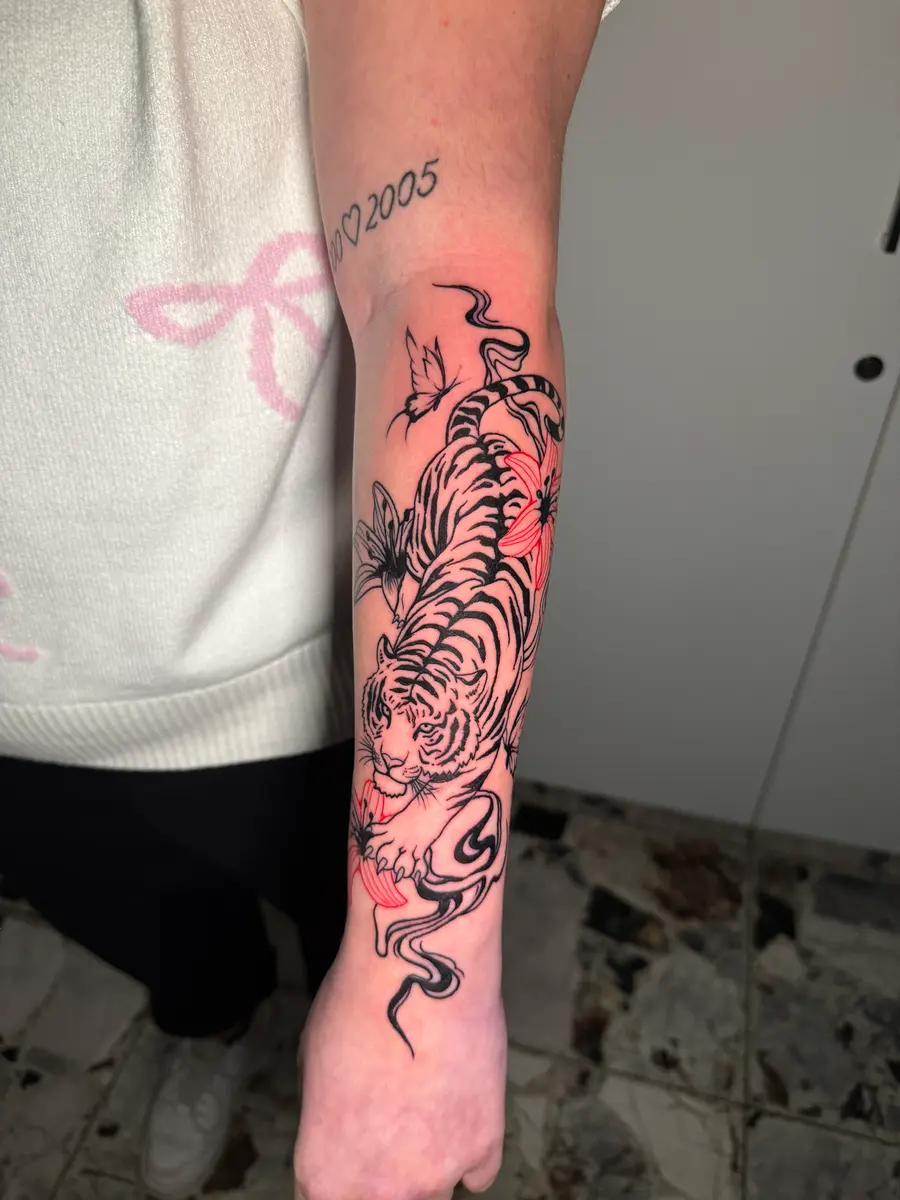 Tiger mit Kirschblüten, Blackwork-Tattoo mit Farbakzenten am Unterarm